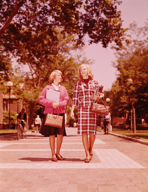 Two blonde female students walking on campus, carrying straw purses and books. (Photo by H. Armstrong Roberts/Retrofile/Getty Images)
