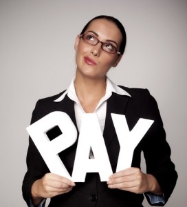 A woman in a suit holding up the word pay
