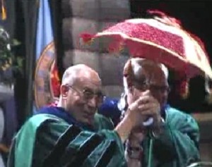 The Dalai Lama holds an umbrella while the band plays at Tulane University's graduation. Screenshot courtesy of WGNO ABC.